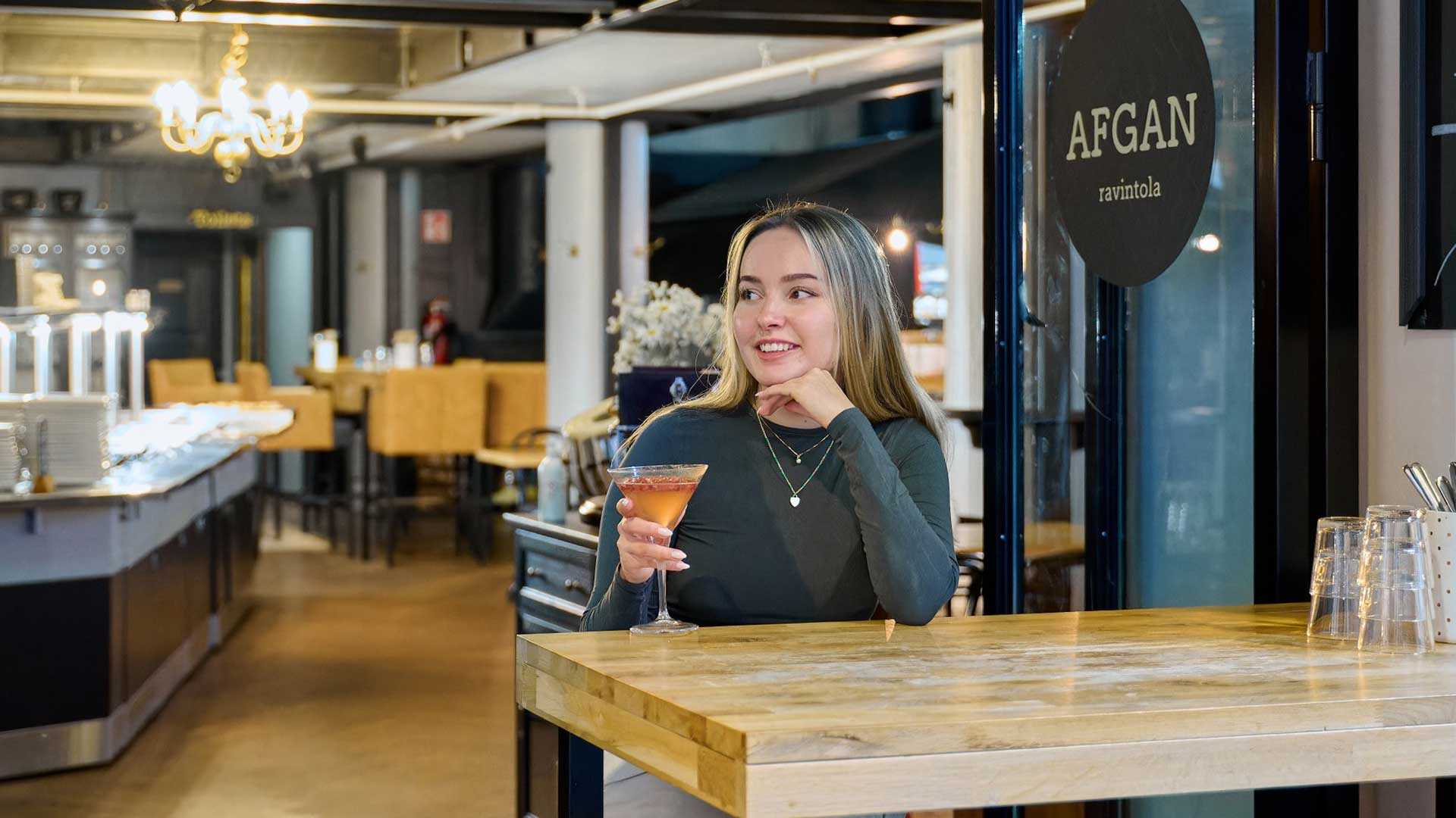 Nainen juo cocktailia ravintolassa Finlaysonin alueella.